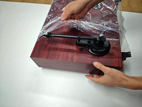 Lift the wrapped turntable and speakers out of the box.